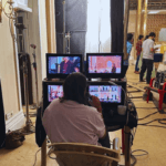 Film director monitoring live camera feeds during a Bollywood movie shoot inside a Mumbai studio