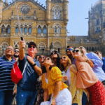 Tourists taking a group photo in front of Chhatrapati Shivaji Maharaj Terminus during a Mumbai city sightseeing tour