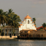 Portuguese-style church beside Goan backwaters with traditional houseboat